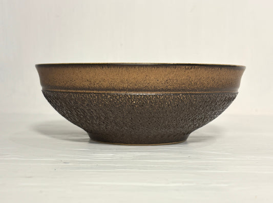 Brown ceramic bowl with textured surface on a white background