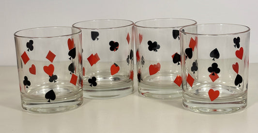 Four clear glasses with playing card suit symbols on a white background