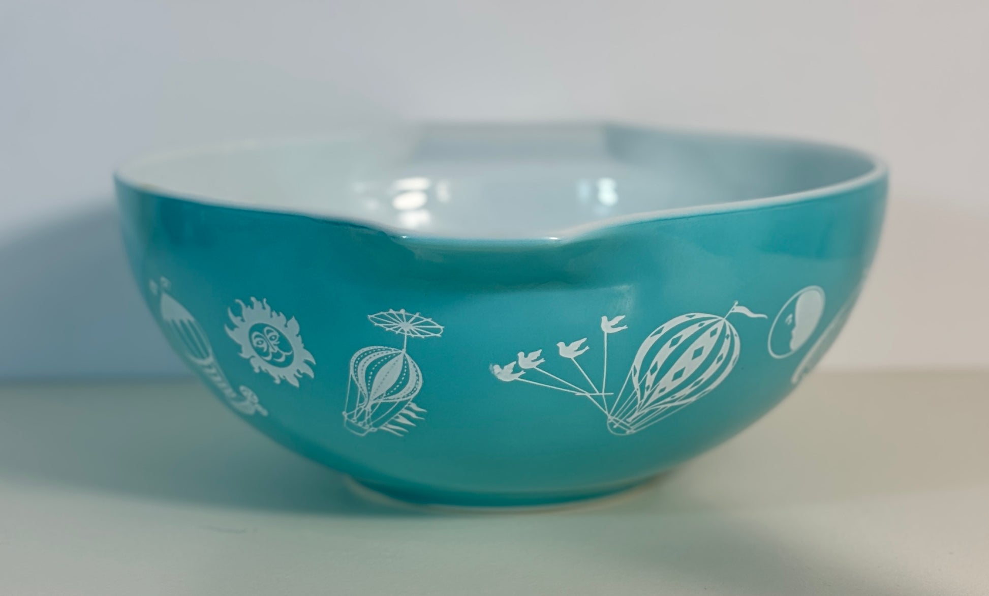 Turquoise bowl with white floral patterns on a white background
