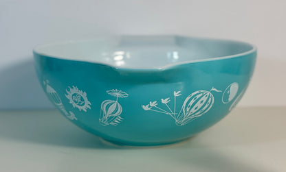 Turquoise bowl with white floral patterns on a white background
