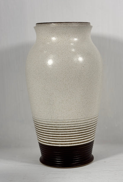 stoneware vase with textured surface and brown base on a plain background