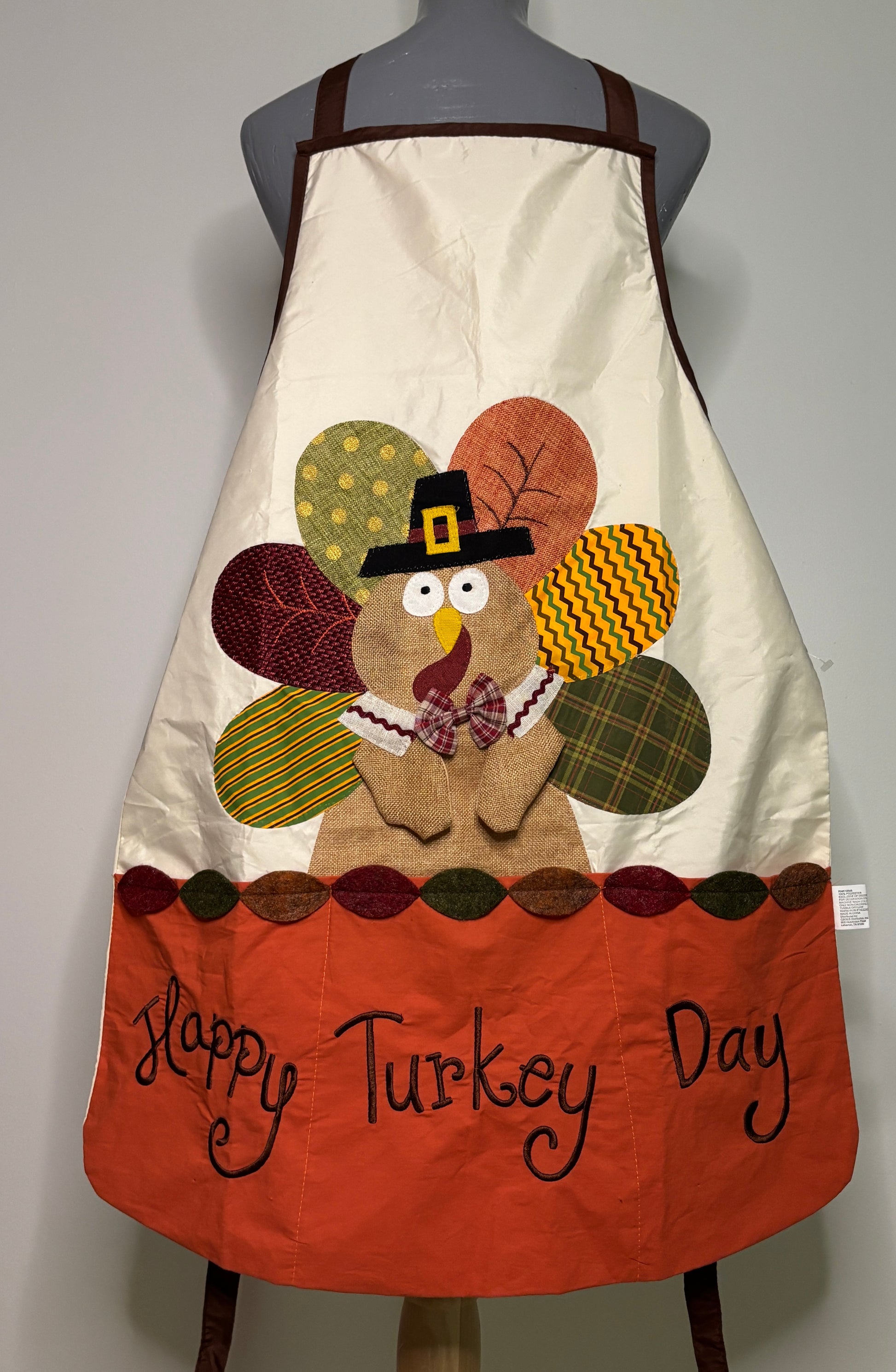 Decorative apron with a turkey design and 'Happy Turkey Day' text on a mannequin.