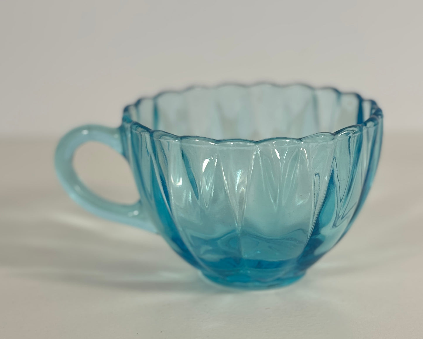 Blue glass teacup with decorative handle on a white background