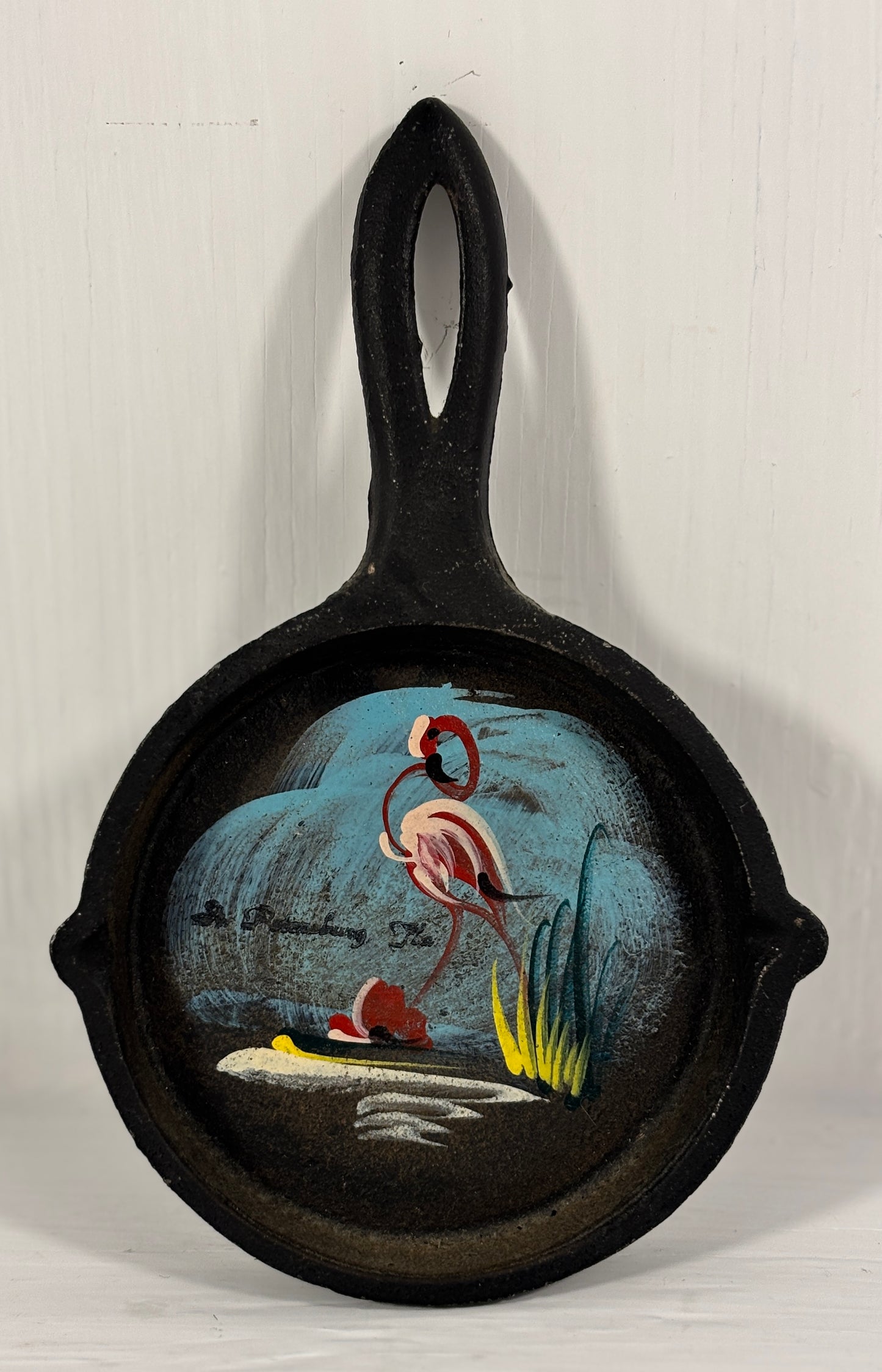 Decorative cast iron skillet with a painted flamingo design on a white background