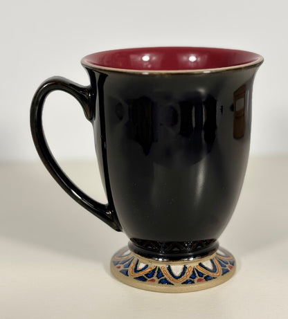 Black mug with a decorative base on a white background