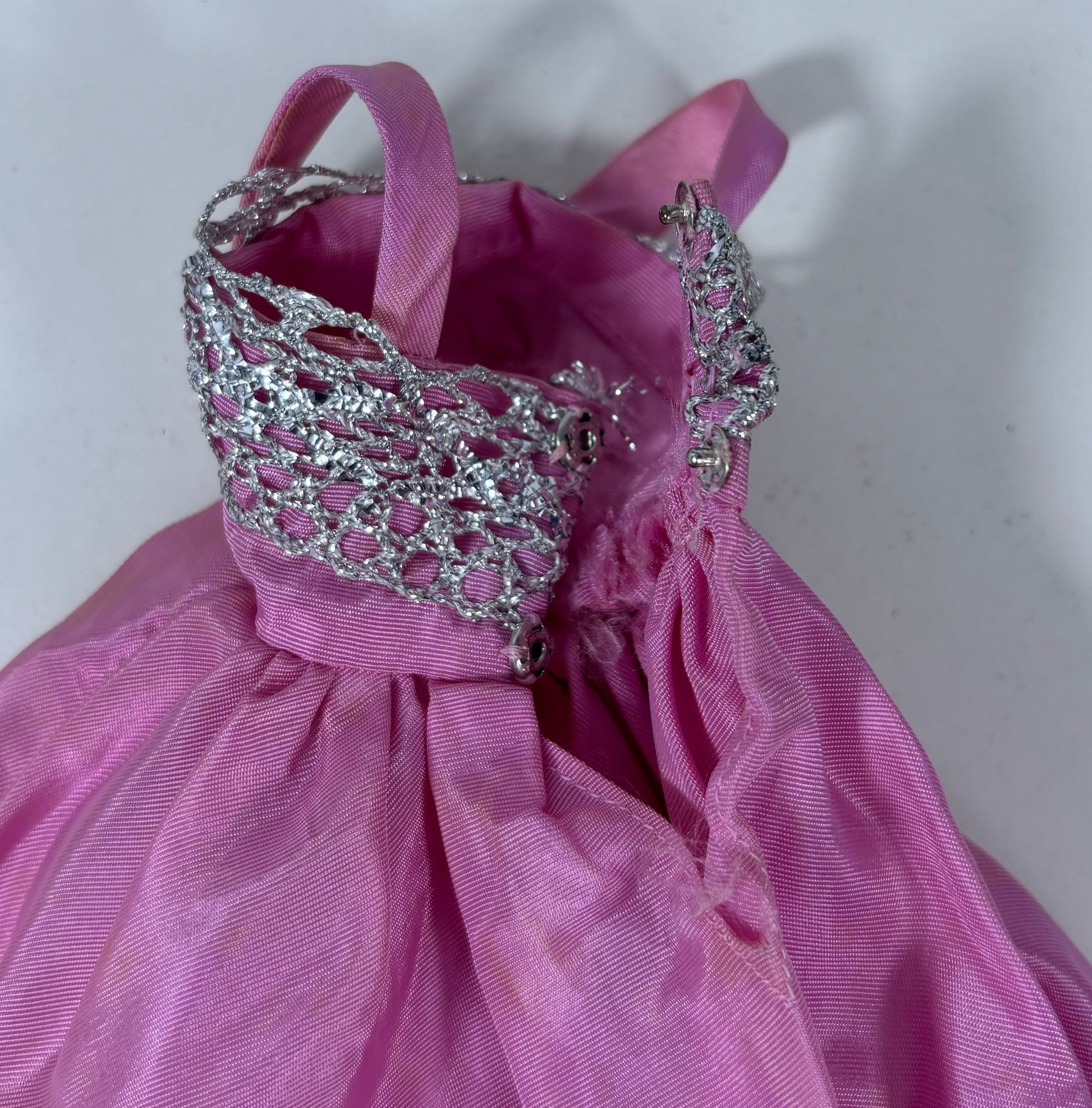 A pink satin dress with a silver rhinestone-embellished collar and matching silver shoulder straps, photographed against a plain light background.
