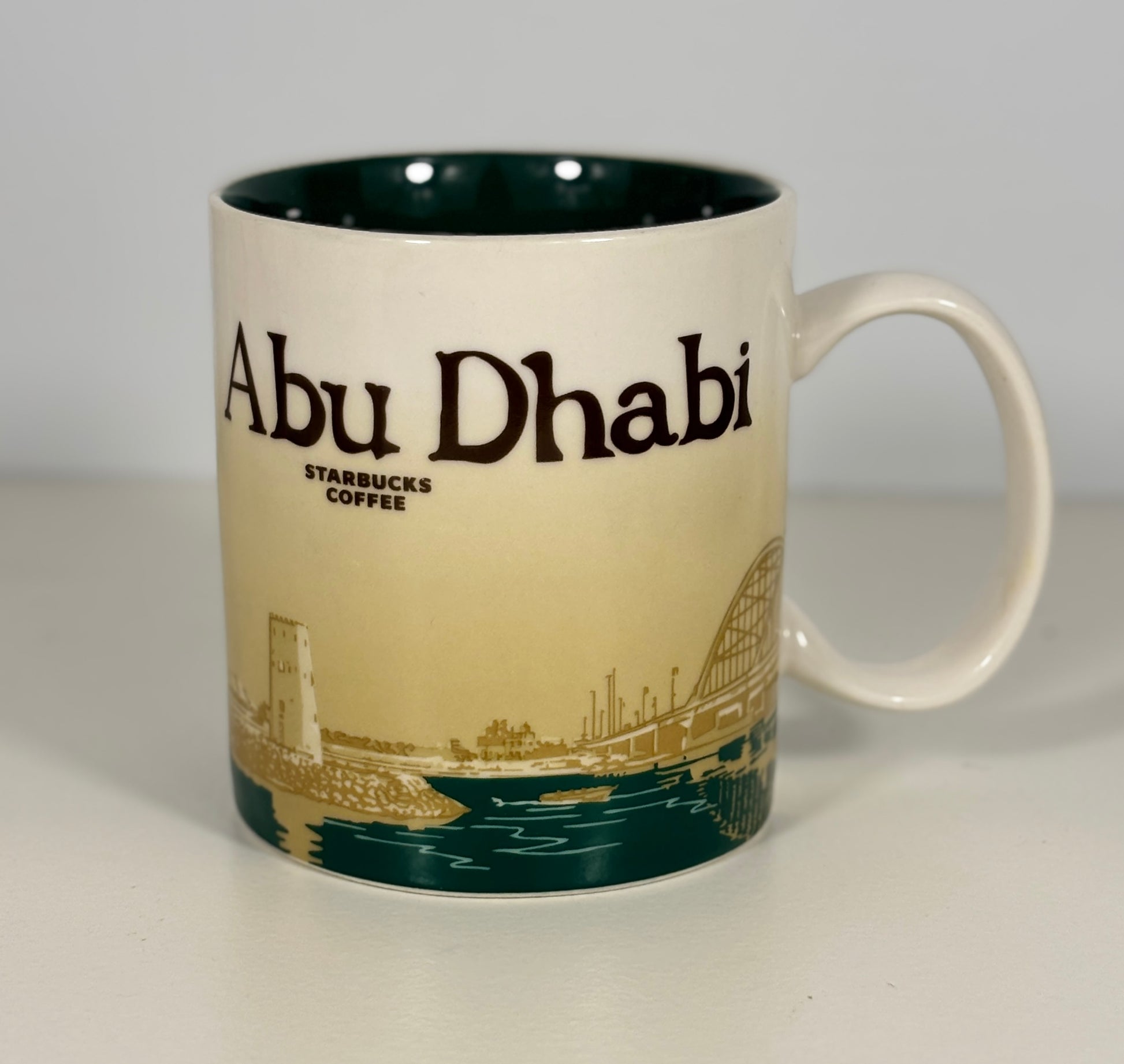 Starbucks coffee mug with 'Abu Dhabi' branding on a plain background
