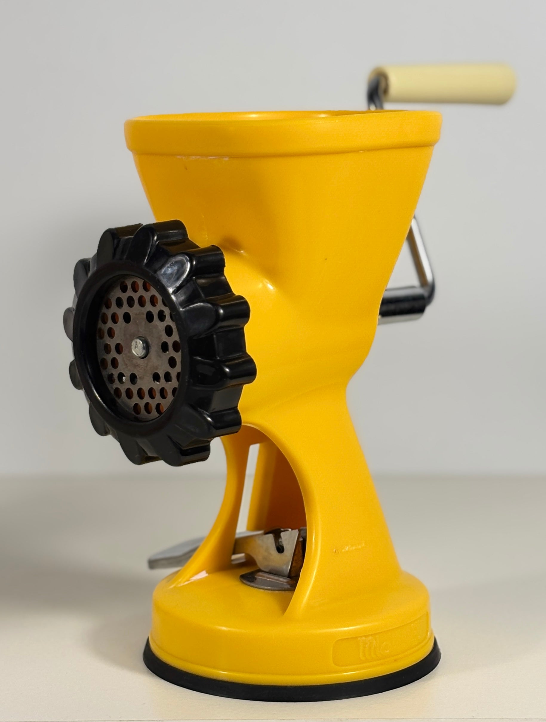 Yellow manual meat grinder on a white background