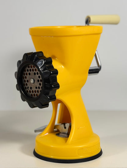 Yellow manual meat grinder on a white background
