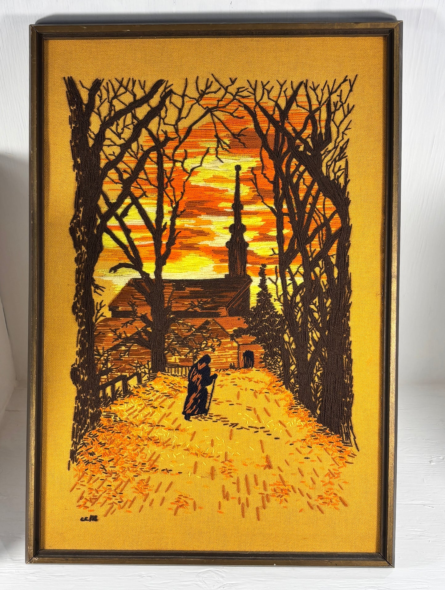 Framed artwork of a silhouette of a church and trees at sunset.
