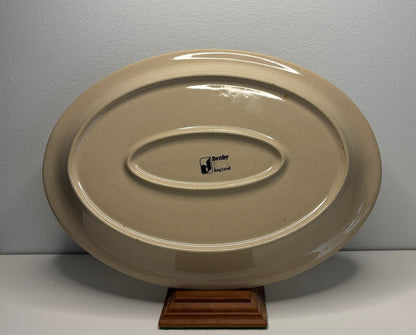 Beige ceramic platter with a visible brand logo on a gray background