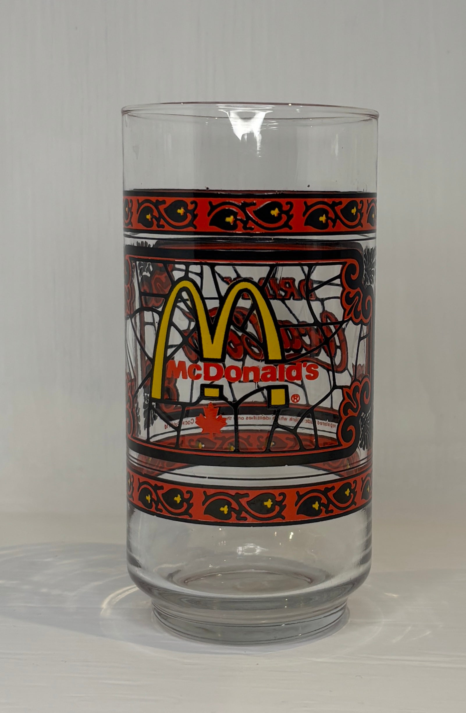 Glass with McDonald's logo and decorative border on a gray background