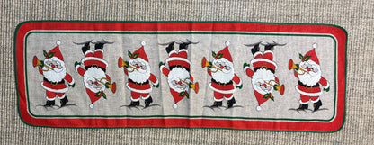 Decorative table runner with Santa Claus illustrations on a textured surface