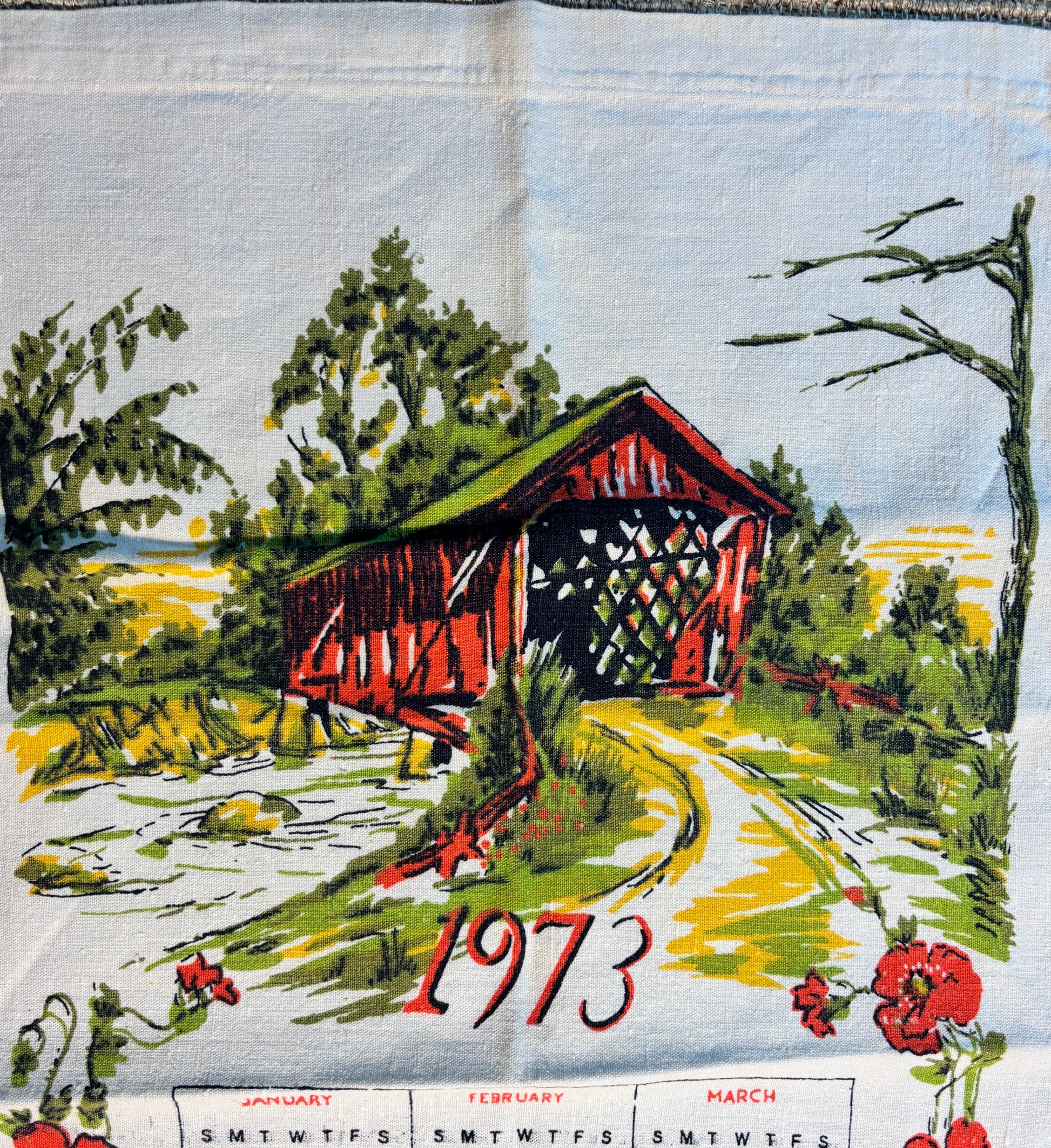 Vintage fabric calendar with a red covered bridge and scenic design, featuring the year 1973.