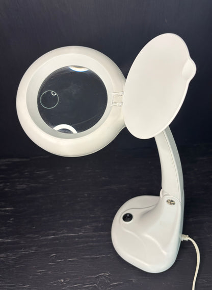 White magnifying glass with a stand on a dark surface