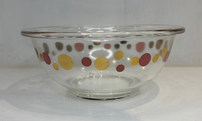 Clear glass bowl with colorful polka dot pattern on a white background