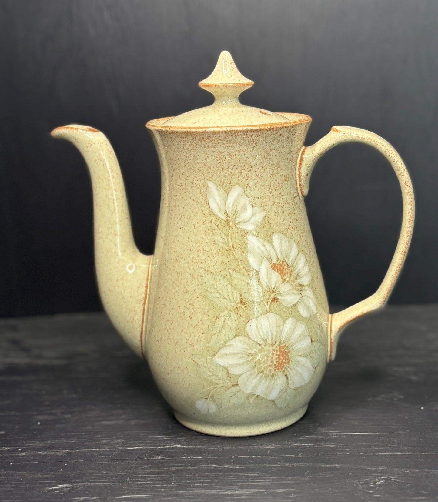 Ceramic teapot with floral design on a dark surface