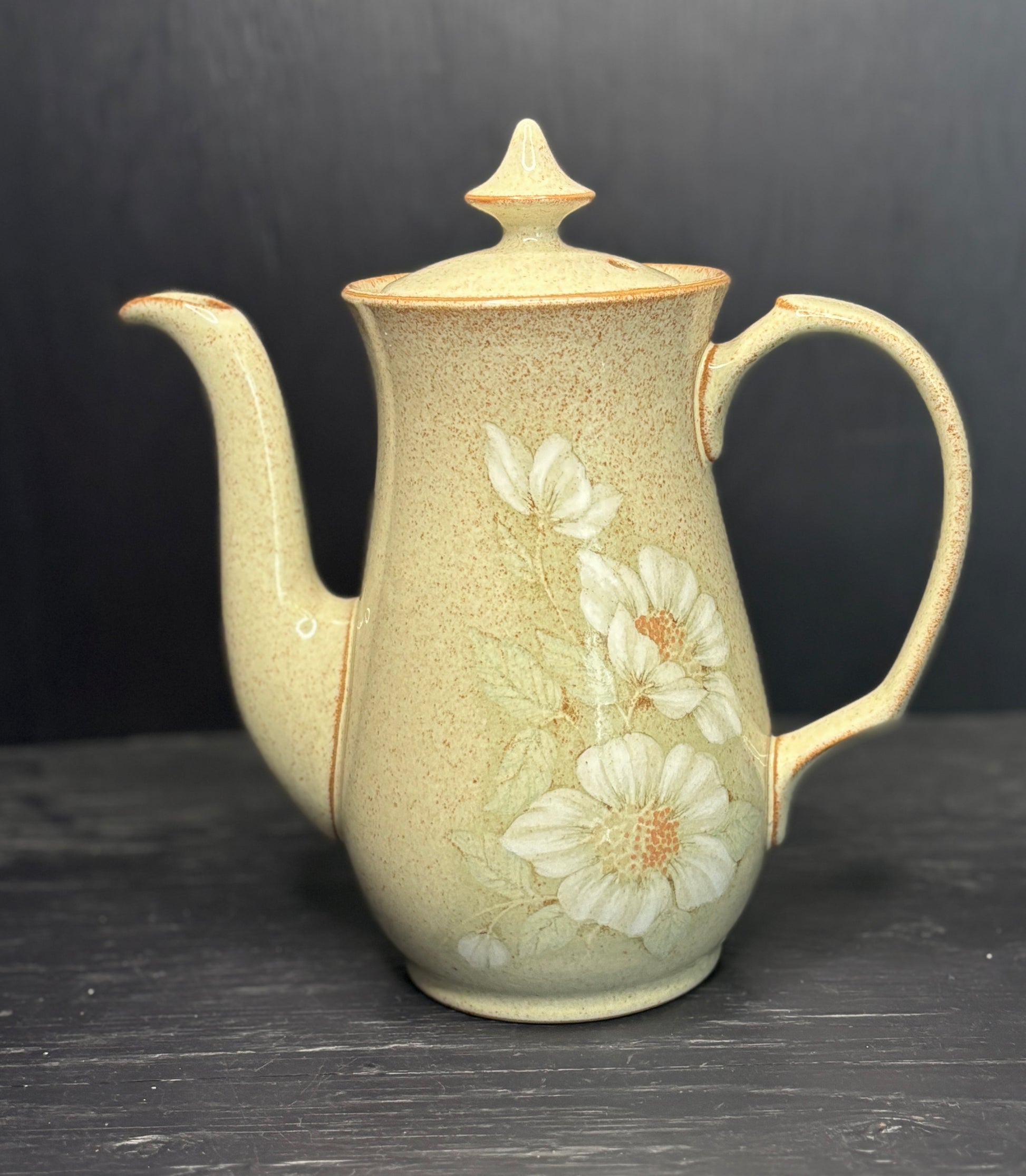 Ceramic teapot with floral design on a dark surface