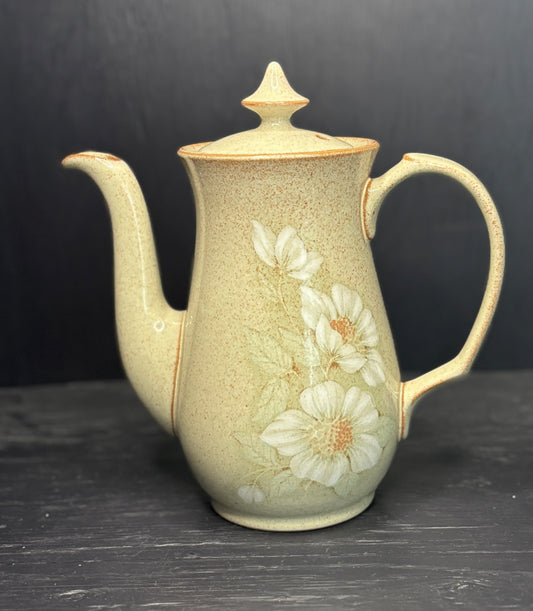 Ceramic teapot with floral design on a dark surface