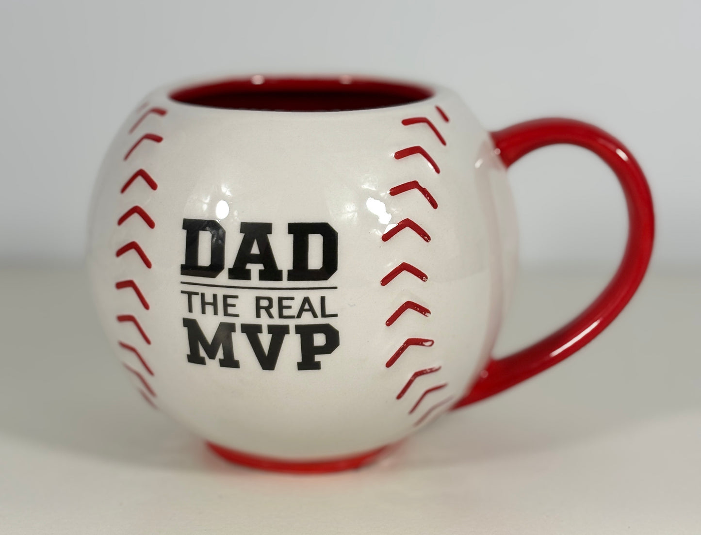 Baseball-shaped mug with 'DAD THE REAL MVP' text on a white background