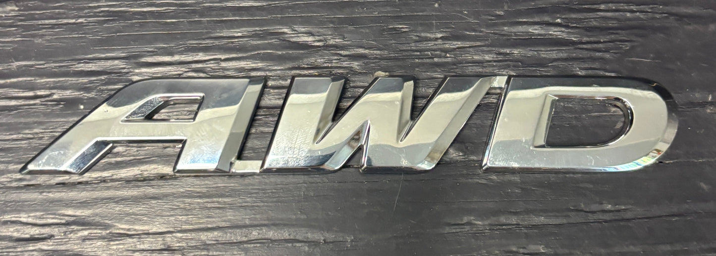 Metallic 'AWD' emblem on a dark background