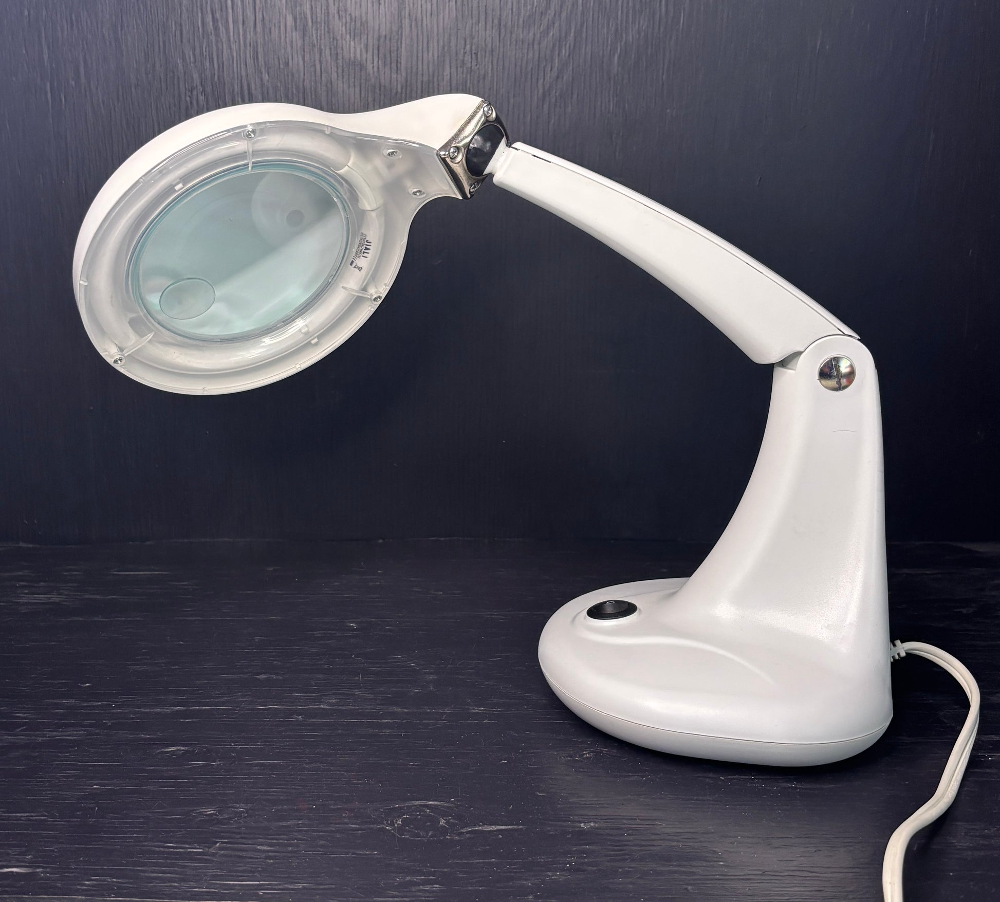 White magnifying lamp on a dark surface