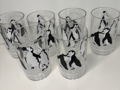 Set of six clear glasses with black and white penguin illustrations on a white background