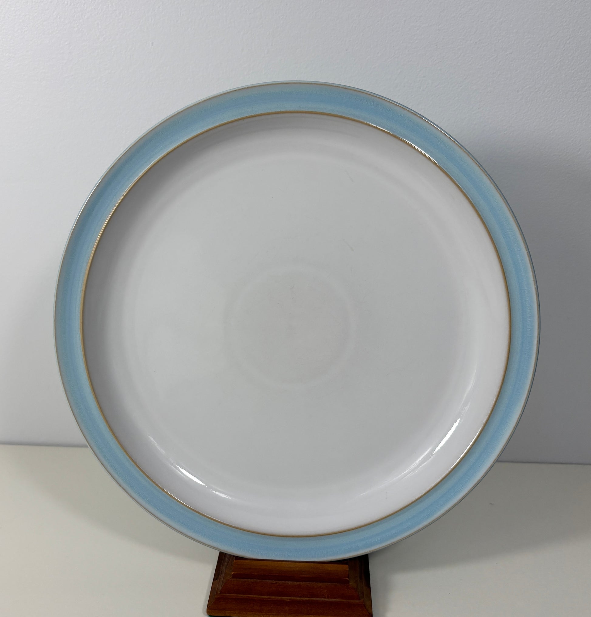 White plate with blue rim on a stand against a white background