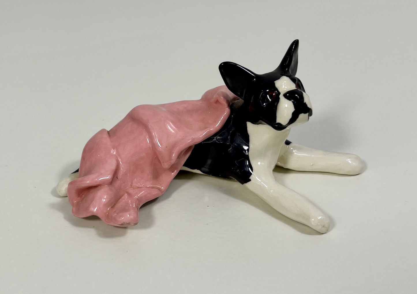 Dog figurine wearing a pink dress on a white background
