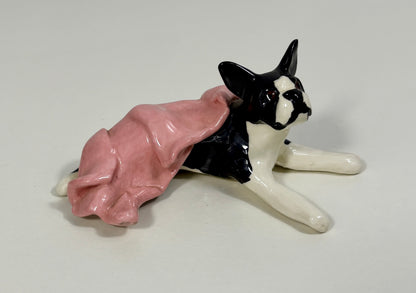 Dog figurine wearing a pink dress on a white background