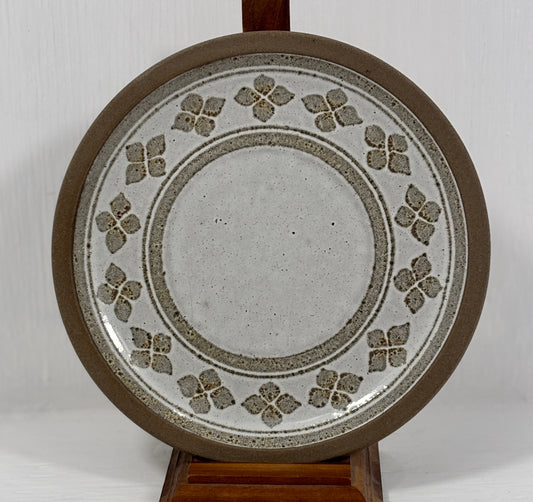 Ceramic plate with decorative pattern on a stand against a white background