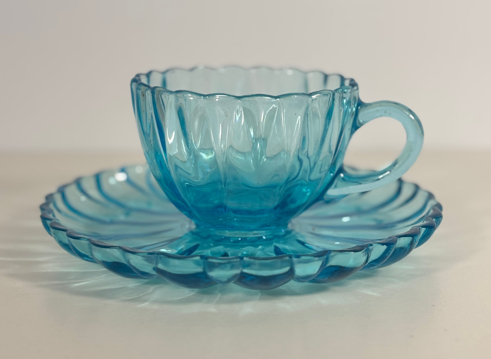 Blue glass teacup and saucer on a white background