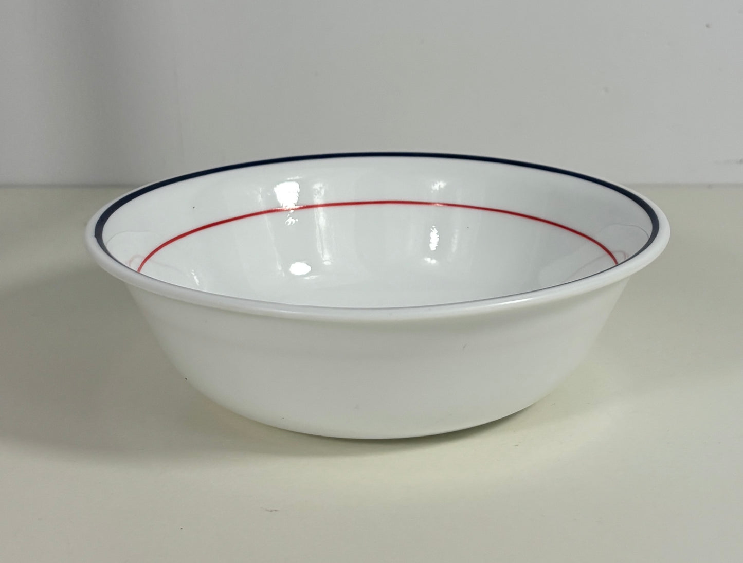 White bowl with red and blue rim on a white background