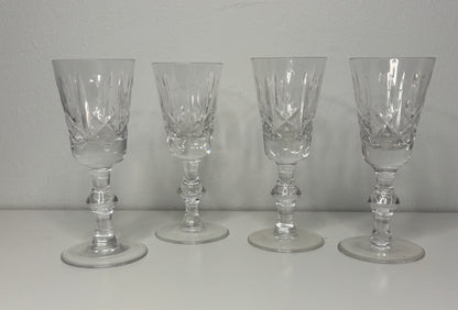 Four clear glass goblets on a white surface with a gray background