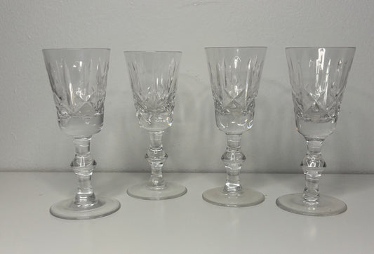 Four clear glass goblets on a white surface with a gray background