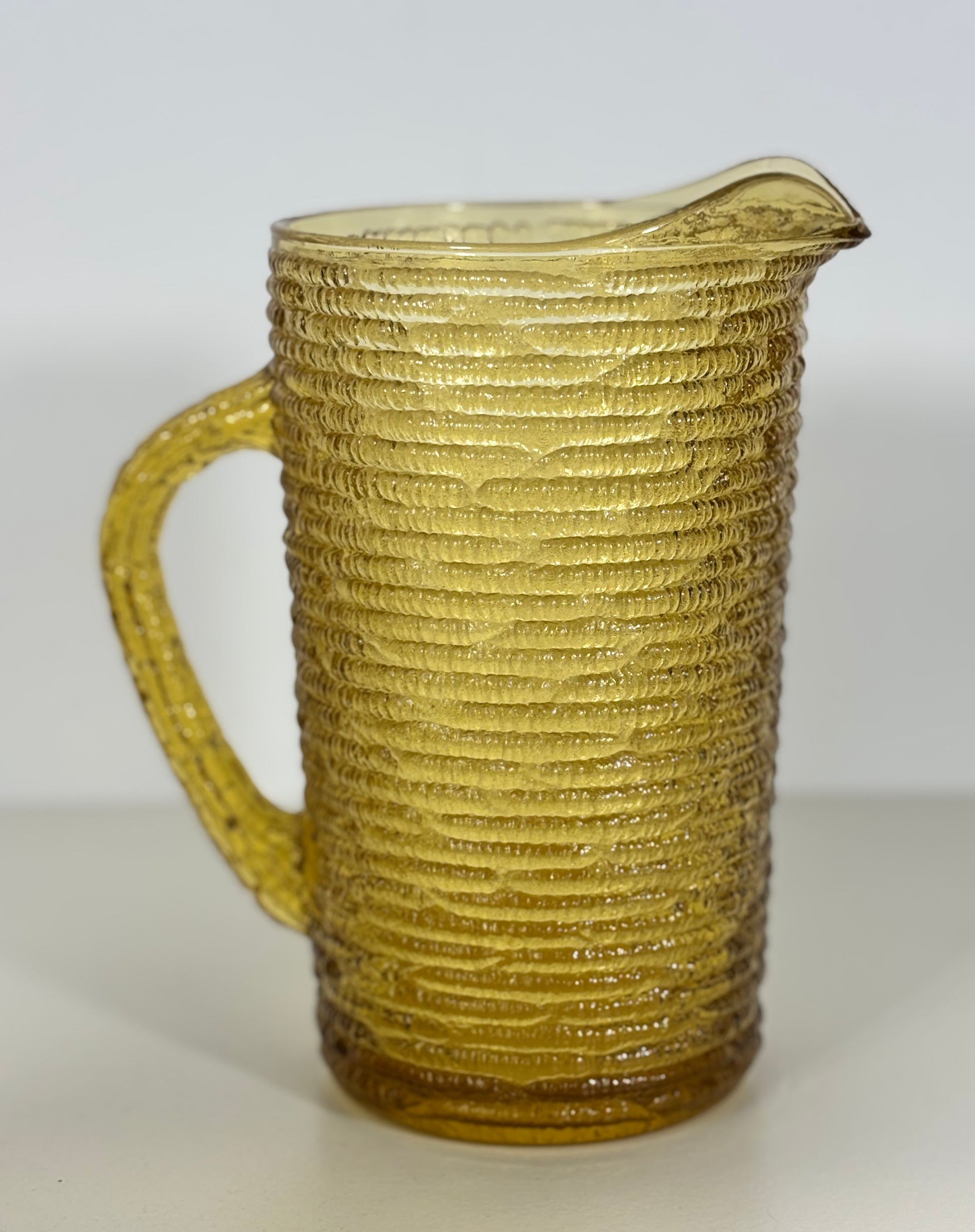 Textured glass pitcher on a white background