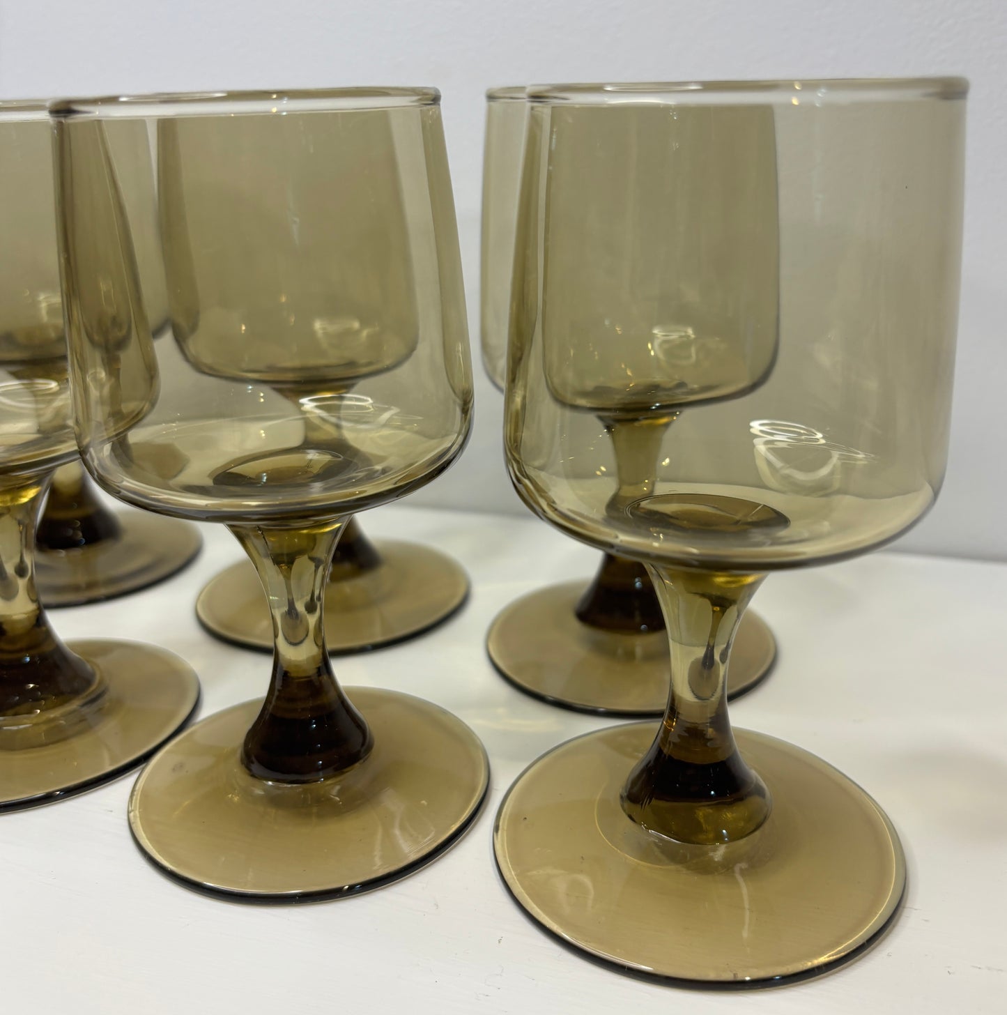 Set of smoked glass wine glasses on a white surface