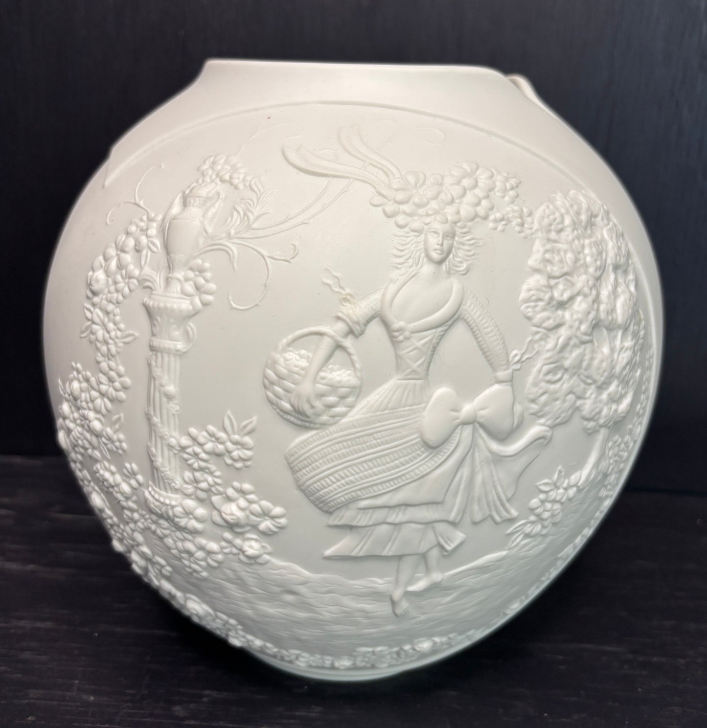 Decorative white ceramic plate with embossed design on a dark background