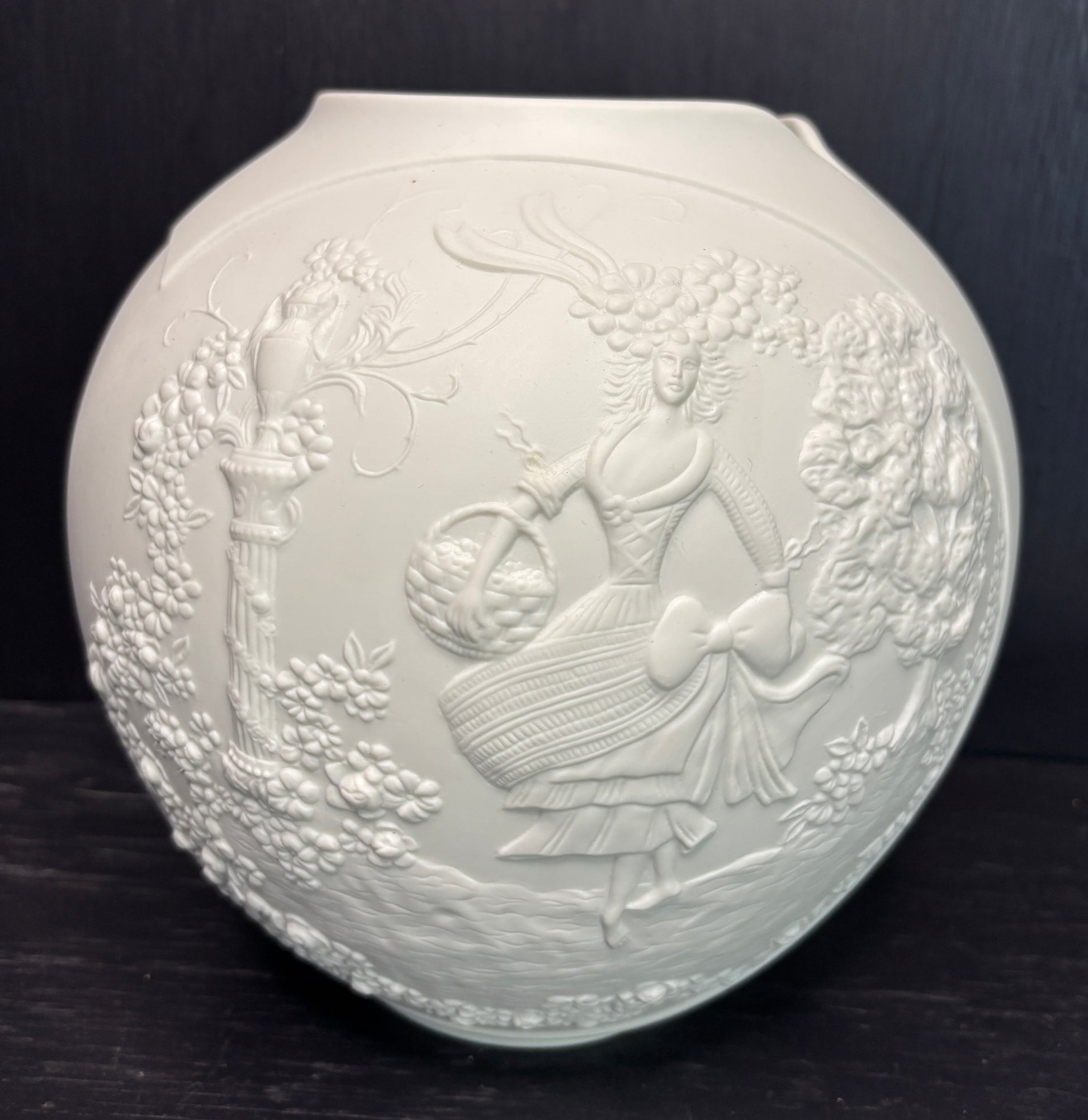 Decorative white ceramic plate with embossed design on a dark background