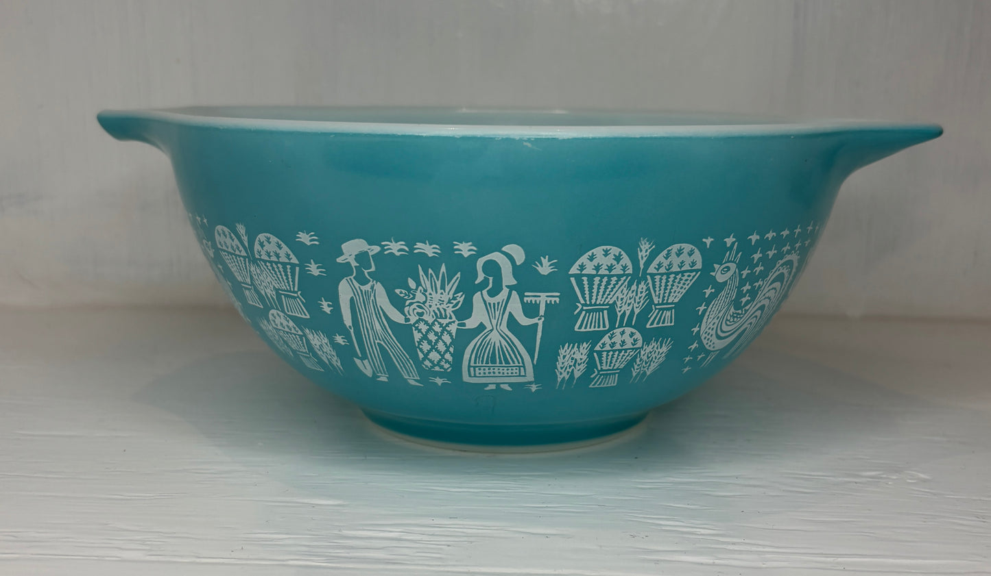 Teal bowl with white decorative patterns on a light gray background