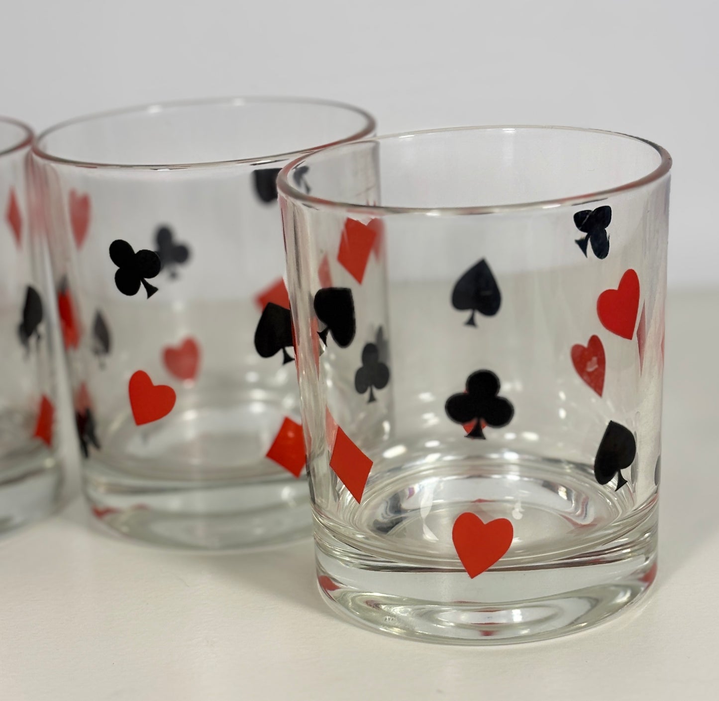 Clear glass tumblers with playing card suit symbols on a white background