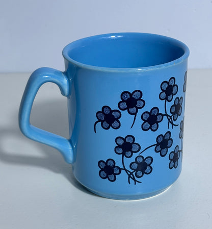 Blue mug with black floral pattern on a light gray background