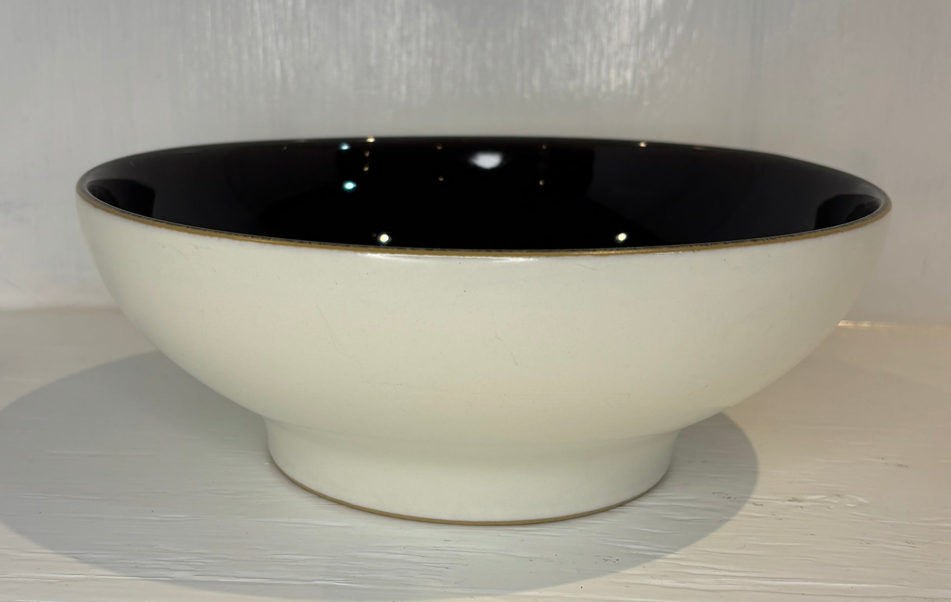 Ceramic bowl with black interior and rim on a light gray surface