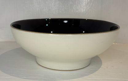 Ceramic bowl with black interior and rim on a light gray surface