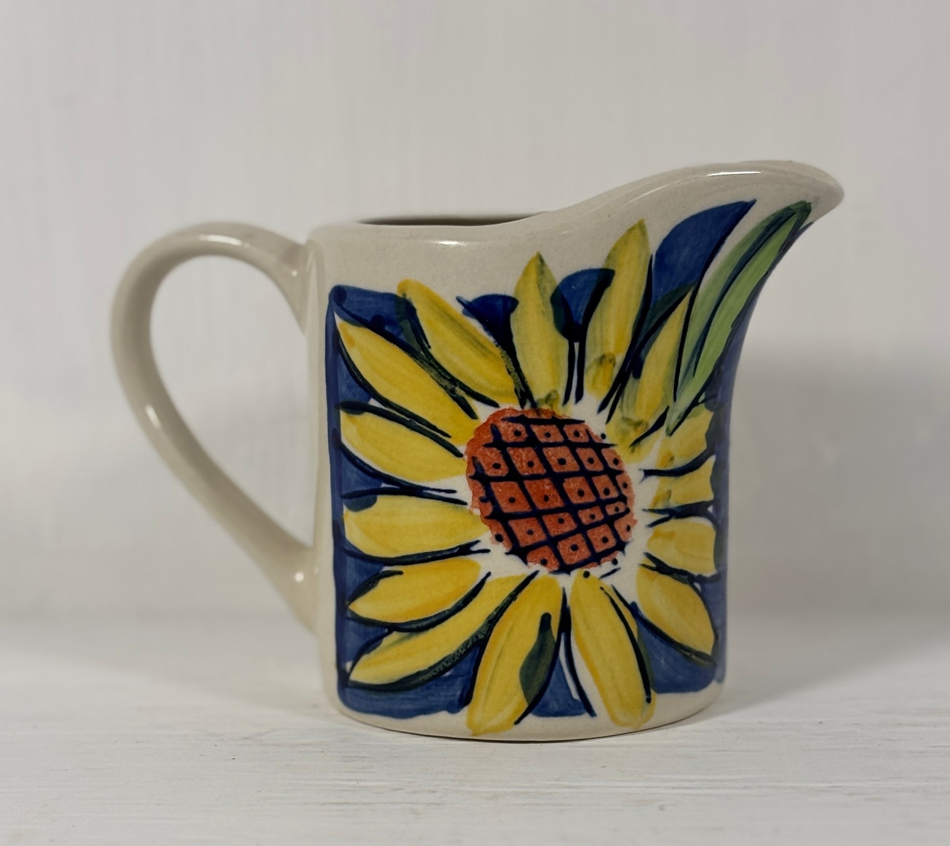 Ceramic creamer with sunflower design on a white background