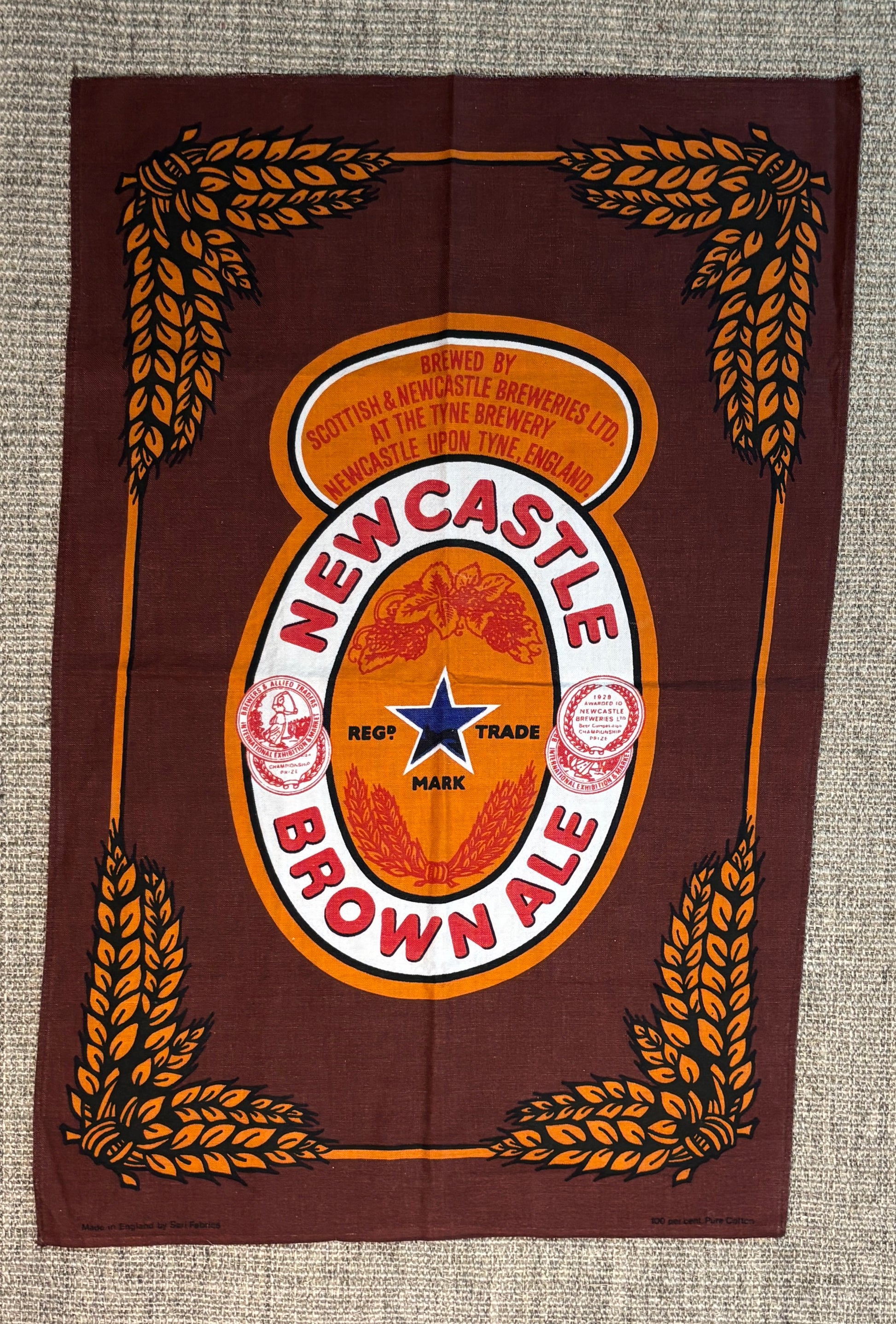 Newcastle Brown Ale logo on a brown background with wheat designs