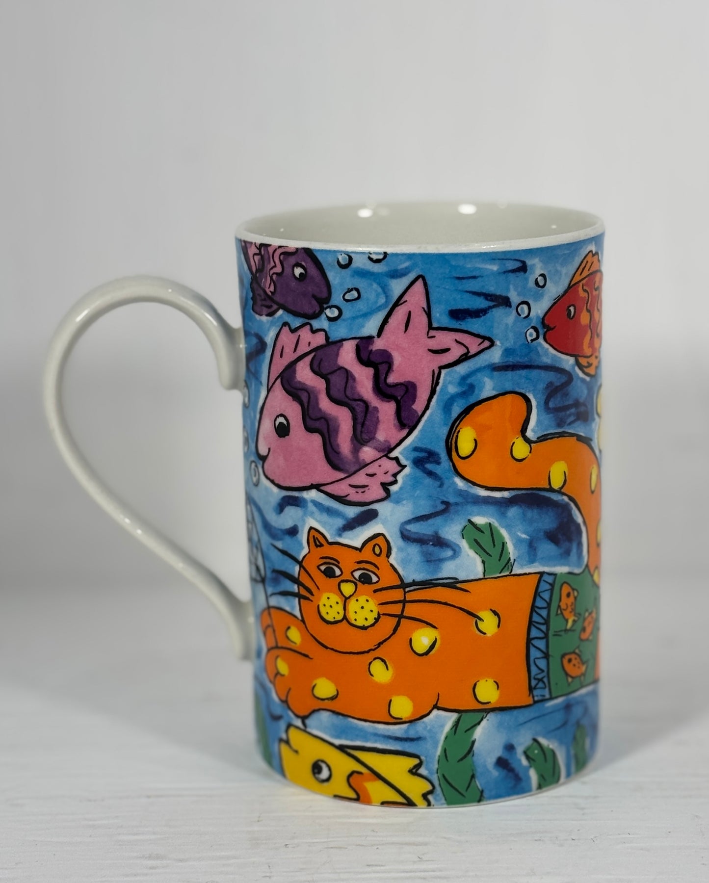 Mug with a colorful fish and cat design on a white background