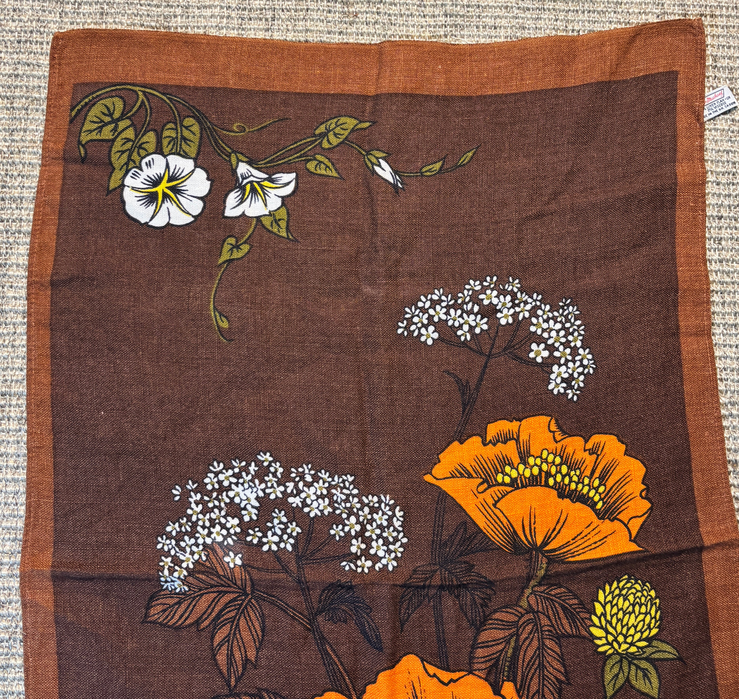 Floral patterned fabric with orange and white flowers on a brown background