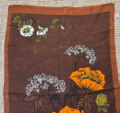 Floral patterned fabric with orange and white flowers on a brown background