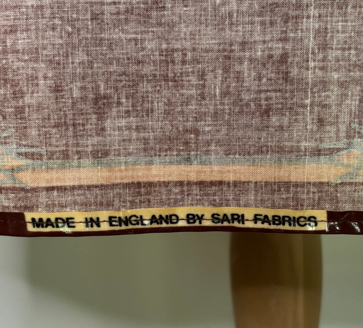 Textile with a label indicating 'Made in England by Sari Fabrics' on a fabric background.
